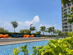 a pool with orange lounge chairs in a park at NEW Batu Kawan 2 Bedrooms Suite near IKEA-Columbia Asia Hospital-BKIP-UOW Kdu in Simpang Ampat