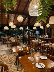 a restaurant with wooden tables and chairs and chandeliers at Pousada Carumbé Lavras Novas in Lavras Novas