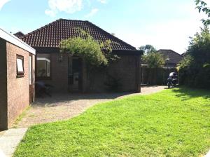 a small brick house with a grass yard at 4-6 persoons bungalow op park bij meer , met zwembad in hoogseizoen in Herkingen +5 photos
