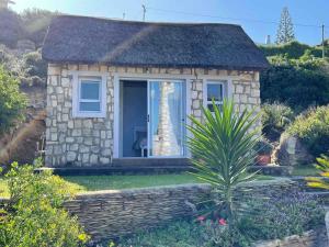 a small stone house with a window in a garden at Under Milkwood in Witsand