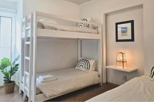 two white bunk beds in a bedroom with a plant at Beach House on Faro Island with a Dreamy Terrace and 7 Beds for the Perfect Escape in Faro