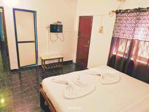 a bedroom with a bed with white sheets and a window at Caitan Villa Candolim in Candolim