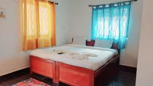 a small bed in a room with blue curtains at Caitan Villa Candolim in Candolim