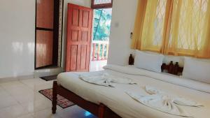 a bedroom with two beds and a red door at Caitan Villa Candolim in Candolim