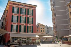 a tall red building with green windows in a city at Palazzo Sant' Agostino - Natural Comfort by THE FIRST in La Spezia