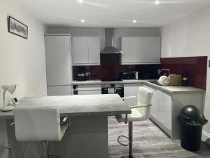 a kitchen with white cabinets and a table and chairs at Keep Green Abode in West Byfleet
