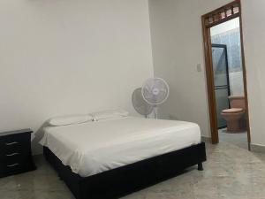 a bedroom with a white bed and a fan at Casa MAVA in Mariquita