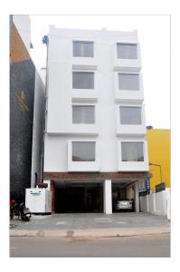a white building with a parking garage in front of it at The Kings Park Residency in Chennai