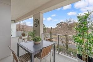 a balcony with a table and chairs and a clock at Glebe Park Cityside with Style in Canberra