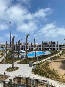 a view of a resort with a pool and palm trees at Luxury 4BRs Penthouse Villa, Marassi in El Alamein