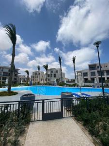 a swimming pool with palm trees and buildings at 4 Bedrooms Penthouse Villa, Marassi in El Alamein