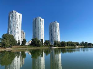 two tall buildings are reflected in a lake at ObolonSky apartament on Obolon in Kyiv