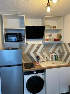 a kitchen with a counter and a refrigerator and a sink at Charmant T1 Bis Cabine - Parking privé in Luchon