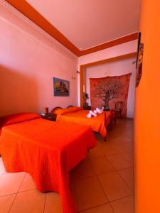 a hotel room with three beds with orange sheets at Beb al porto da joseph in Trapani