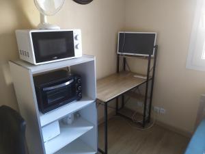 a microwave oven sitting on top of a stand with a microwave at Studette COSY 2 couchages proche TOURS in Tours