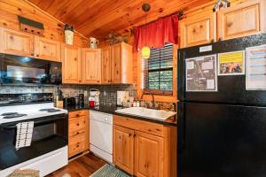 a kitchen with wooden cabinets and a black refrigerator at In Green Pastures Gatlinburg in Sevierville +23 photos