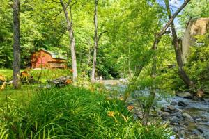 a river with a barn and a house in the background at In Green Pastures Gatlinburg in Sevierville