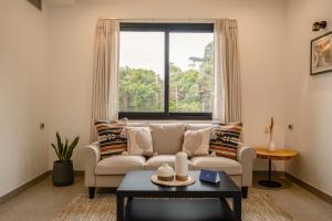 VeremSaffronStays Vento - 4BR villa with pool, elevator, chic interiors & sunlit spaces, near Candolim, Calangute & Baga的带沙发和窗户的客厅