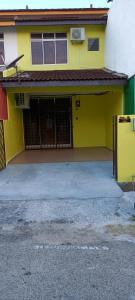 a yellow building with a gate and a garage at Homestay RAHMAJID in Segamat