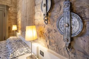 a bedroom with a stone wall with a bed and a lamp at Casa Ancora in Carloforte
