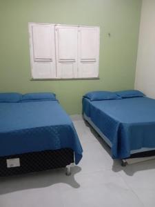 two beds in a bedroom with blue sheets and a window at Casa Santos in Santo Amaro +10 photos