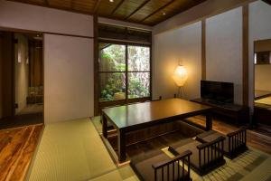 a room with a table and chairs and a window at Natsume an Machiya House in Kyoto