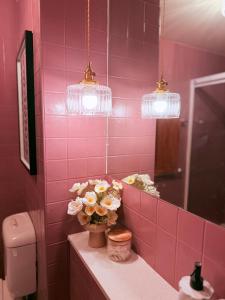 Un baño con azulejos rosas, un jarrón de flores y luces. en Timeless Emporium stay with city view, en Melbourne 20 fotos más