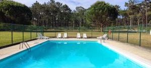 a swimming pool with chairs and a fence at HI Ovar - Pousada de Juventude in Ovar