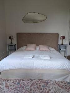 un grande letto bianco con due cuscini rosa sopra di Chambre d'hôte - petit château à la campagne a Saint-Aubin-Epinay