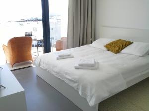 a bedroom with a white bed with two towels on it at Sargo, vistas espectaculares entre mar y volcán in Punta de Mujeres