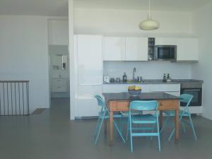 a kitchen with a wooden table and blue chairs at Sargo, vistas espectaculares entre mar y volcán in Punta de Mujeres +8 photos