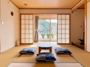a room with a table and pillows on the floor at FUWARI-kumamoto- in Aso