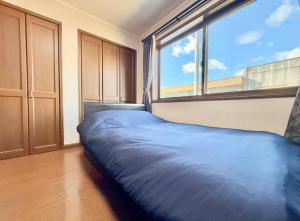 ein Bett in einem Zimmer mit einem großen Fenster in der Unterkunft FUWARI-kumamoto-12時チェックアウトでゆったり滞在 パターゴルフと絶景を楽しむ1日1組宿 in Aso