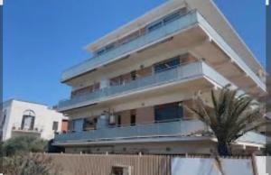 a tall building with a palm tree in front of it at Appartamento Jungle Beach in Lido di Ostia