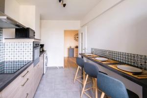 a kitchen with a counter with blue chairs in it at Le Grandmont - 100m du parc - au pied de la faculté des sciences in Tours