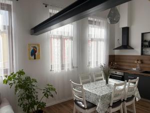 a dining room with a table and chairs and a kitchen at Jégmadár Vendégház in Baja