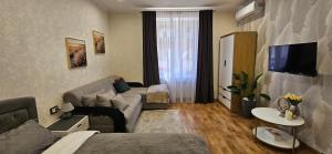 un soggiorno con un divano e una TV di Затишні апартаменти зі сховищем на Святогеоргієвській 15 a Kryvyj Rih