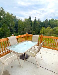 a glass table and two chairs on a deck at Gîte du Ruisseau in Lamarche