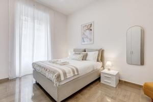 a white bedroom with a bed and a mirror at FaMa - Mecenate 3BR & 2BA in Rome