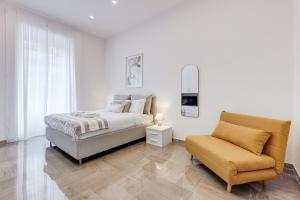 a white bedroom with a bed and a chair at FaMa - Mecenate 3BR & 2BA in Rome