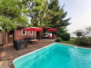 a house with a swimming pool and a patio with red umbrellas at Gîte le 308 Chambre bord de l'eau oka in Oka