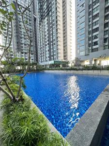une grande piscine bleue en face de grands bâtiments dans l'établissement KL 7-9 Pax Lux&Premium Near Farm In The City, à Gua Sai