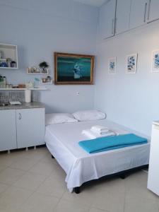 a white room with a bed and a kitchen at Bluefullstop-Μπλε Τελεία in Artemida