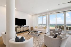 Una sala de estar con muebles blancos y grandes ventanales. en Luxurious Penthouse Condo with Stunning Gulf Views! #402 Viridian in Seagrove 5BR Sleeps 12 condo, en Santa Rosa Beach