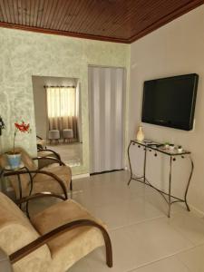 a living room with a flat screen tv on the wall at Sossego e Fé in Ouro Fino
