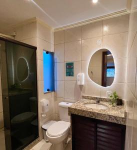 a bathroom with a toilet and a sink and a mirror at Chamos Hostel Cultural in Arraial do Cabo