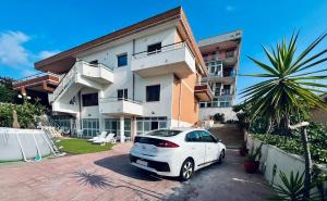 a white car parked in front of a building at Domus Apartment in villa, swimming pool and private parking in Gravina di Catania