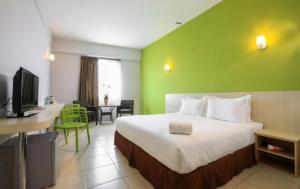 a hotel room with a bed and a desk with a television at HP Temasek Hotel in Malacca