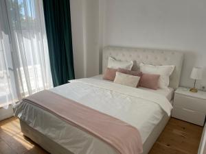 a bedroom with a large white bed with pink pillows at House Garden in Bucharest
