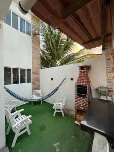 a patio with a hammock and chairs and a grill at Casa paraíso dos milagres in São Miguel dos Milagres